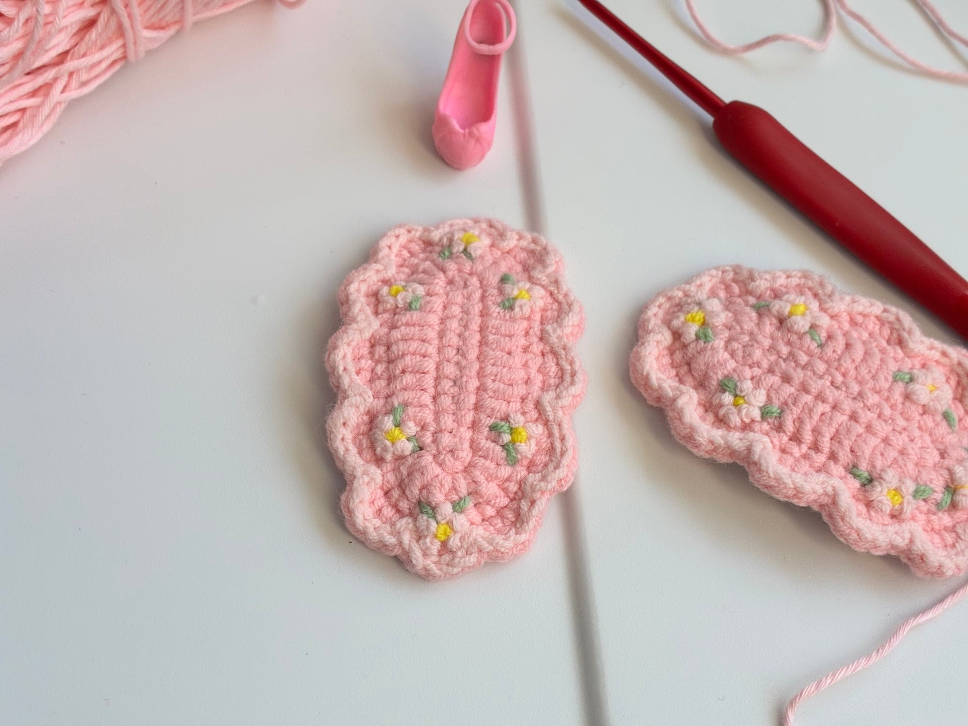Crochet baby girl clip in cotton candy pink with yellow and white embroidered flowers and green leaves