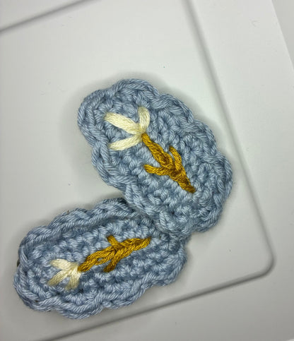 Soft blue handmade crochet hair clip with golden stem and ivory flower embroidery – elegant botanical barrette for baby and toddler girls