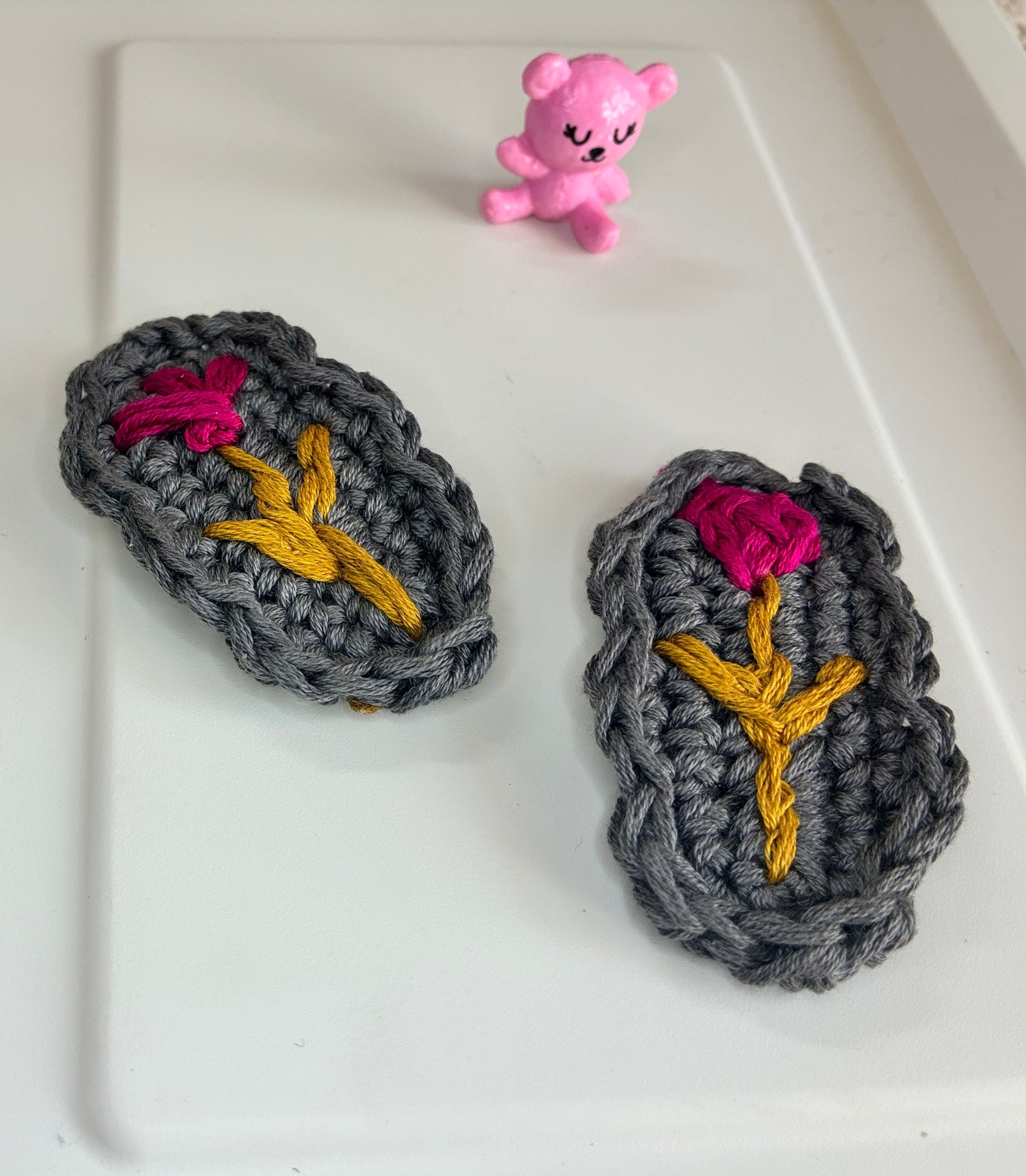 Charcoal grey yarn hair clips with bold pink flowers and gold stems – eco-friendly crochet accessories for toddlers